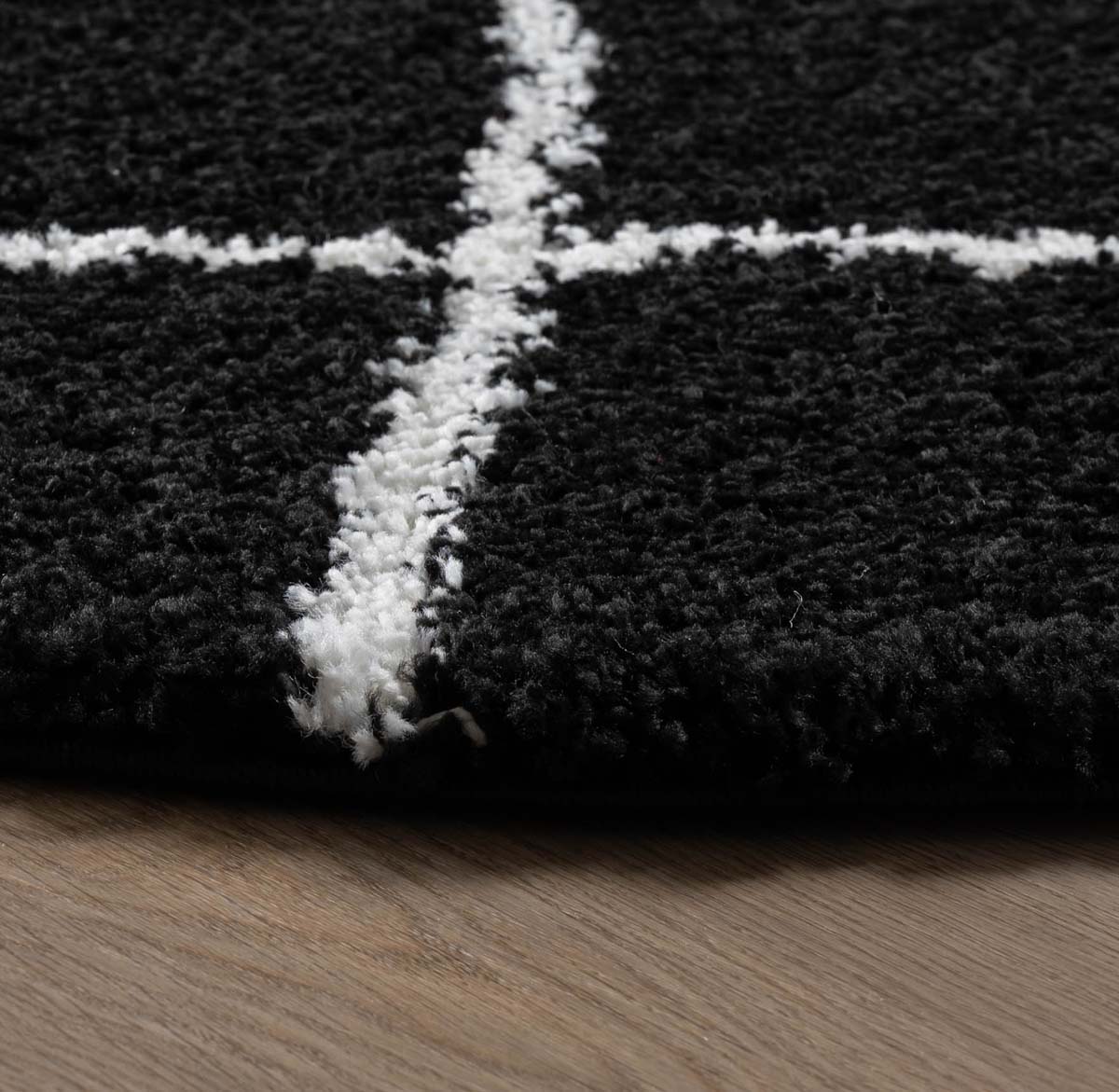 Alfombra redonda a rombos de pelo largo Artisan Artisan - Negro/Blanco - close up zijkant Alfombra redonda a rombos de pelo largo Artisan Artisan - Negro/Blanco - close up zijkant