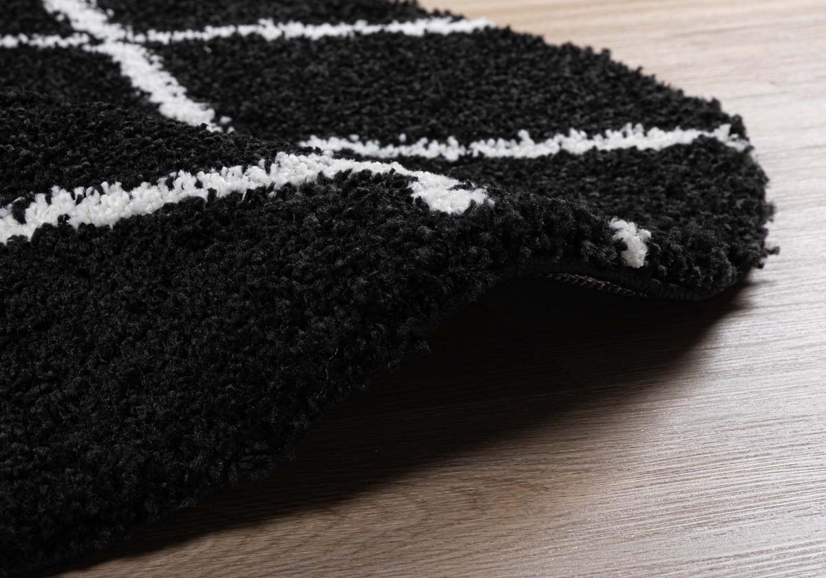 Alfombra redonda a rombos de pelo largo Artisan Artisan - Negro/Blanco - close up zijkant Alfombra redonda a rombos de pelo largo Artisan Artisan - Negro/Blanco - close up zijkant